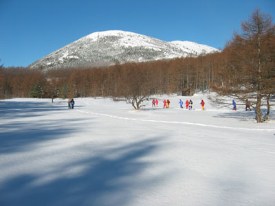 湯ノ丸山を見ながら雪原を歩いている写真