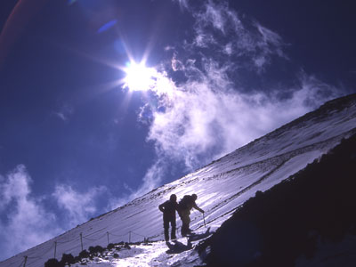 太陽の降り注ぐ斜面を登っている人の写真