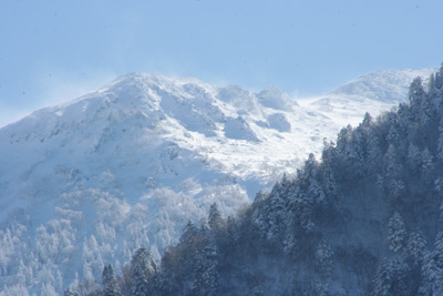 平湯から見た雪煙を上げる乗鞍岳の写真