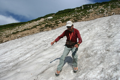 雪渓を足で滑っているＡさんの写真
