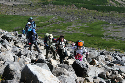 岩の多い登山道を登っている写真
