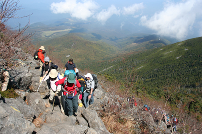 岩場を登っているメンバーと、後に広がる山麓の写真