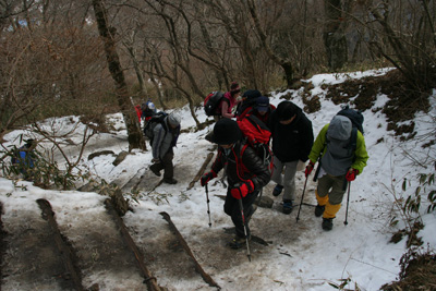 男体山山頂への雪の多い道を登っている写真