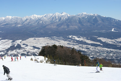 富士見パノラマスキー場でスキーをする人と八ヶ岳の写真
