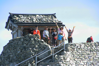 雄山神社でバンザイするメンバーの写真