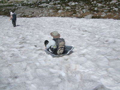 Ｍ．Ｙさん撮影のテントマットを尻に敷いて雪渓をすべるＫ．Ｙさんの写真
