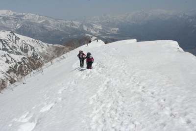 小遠見山直下の雪庇の張り出した尾根を登っている写真