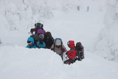 雪と格闘して登ってくるメンバーの写真