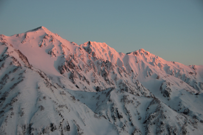 朝日が山頂付近をピンクに染めている白馬三山の写真