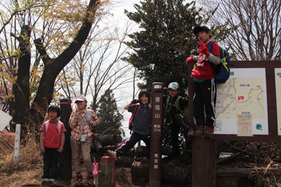 景信山山頂の標識に集まった子どもたちの写真