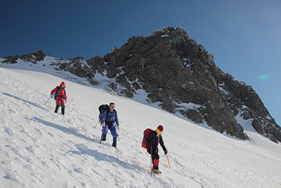 槍ヶ岳を背に下山しているメンバーの写真