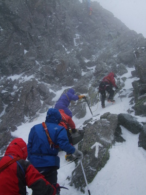 ４日に雪が降る中、山頂を目指して岩場を登っているメンバーを下から撮った写真