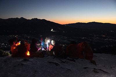 入笠山山頂で日の出を待ちながらツェルトにくるまったりコンロに火をつけたりしている写真