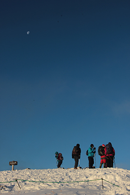 下弦の月と山頂に立つメンバーの写真