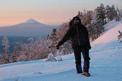 日の出の時間に富士山を背に立っているKNさんの写真