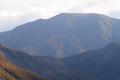清水峠の送電線監視所とその向こうにある檜倉山の写真