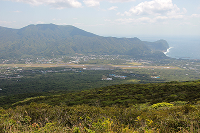 八丈富士の登りから見た八重根漁港方面と三原山の写真
