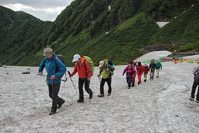 ２日目の朝、涸沢を背に雪渓を登るメンバーの写真