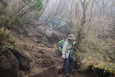 神山から滑りやすい岩の多い道を下っている写真