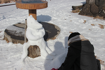 雪で作った馬のモニュメントと作った子の写真