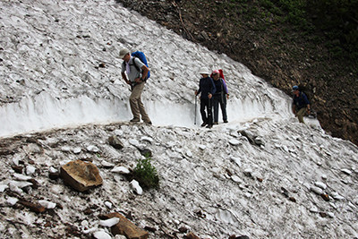 雪渓を切って作られた道を歩いている写真