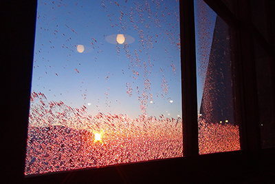 夕日を受けて小屋のガラスに付いた氷が赤く輝いている写真