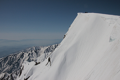 白馬岳山頂と主稜の雪壁を登る人たちの写真