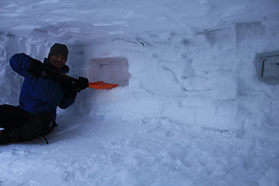 広い雪洞の中で棚を作っているTさんの写真