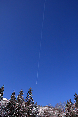 真っ青な空に伸びる飛行機雲の写真