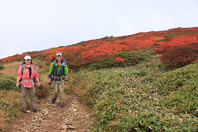 平標山に向かう尾根上の美しい紅葉を背にした２人の写真