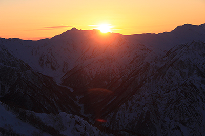 笠ヶ岳の横に沈む夕日の写真