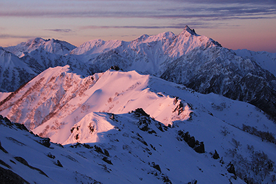 モルゲンロートに染まる表銀座の稜線と槍穂高連峰の写真