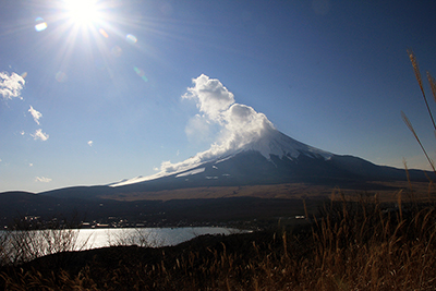 噴煙のような雲がわく富士山と山中湖、太陽の写真