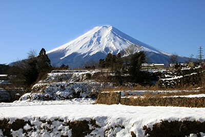 登山口前の車道から見た周辺の雪景色と富士山の写真