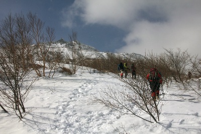 茶臼岳山頂付近の岩峰を上に見て登っている人たちの写真