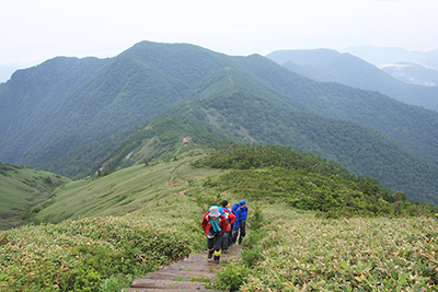 大源太山と平標山ノ家を背に登ってくるメンバーの写真