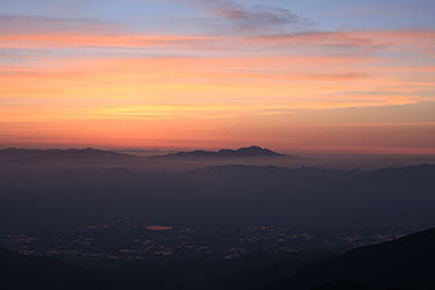 日の出前のあかね色の空とシルエットの浅間山、そして安曇野の写真