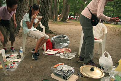 キャンプ場でコンロで野菜を焼いて食べている写真