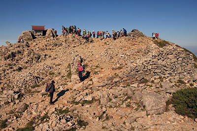 大勢の人が立つ木曽駒ヶ岳山頂の写真
