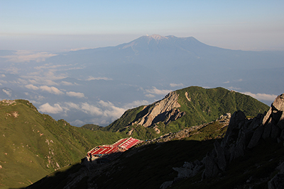 木曽駒ヶ岳山頂から見た頂上木曽小屋と御岳の写真