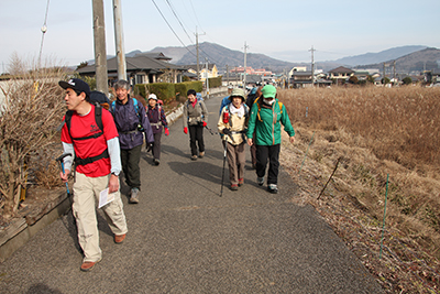 富谷山を背に舗装道路を歩いている写真