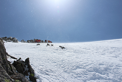 急な氷雪壁の上で下る準備中のガイドさんのグループの写真