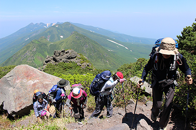 三ッ峰、硫黄山等を背に見ながら、羅臼岳山頂に向かって登っている写真