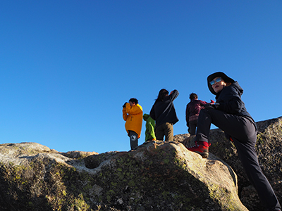 Iさんが撮影した山頂の岩に登っているメンバーの写真