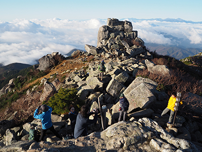 Iさんが撮影した五丈岩と山頂で記念写真を撮るメンバーの写真