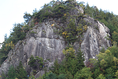 父岩・母岩と思われる岩場と登っているクライマーの写真