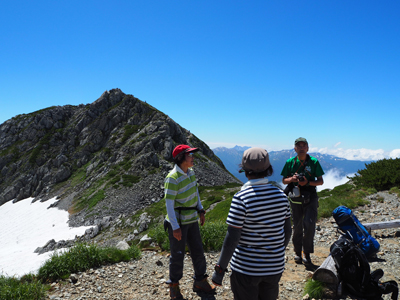 Iさんが撮影した竜王岳を背に、メンバーが話をしている写真