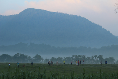 朝霧にかすむ墨絵のような山と思い思いに風景を楽しむ人たちの写真