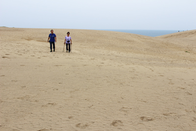 月の沙漠のような広い砂浜を歩いているKさんとIさんの写真