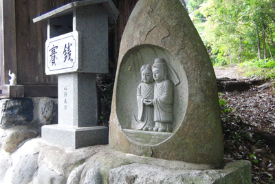 石でできた賽銭箱と道祖神の写真